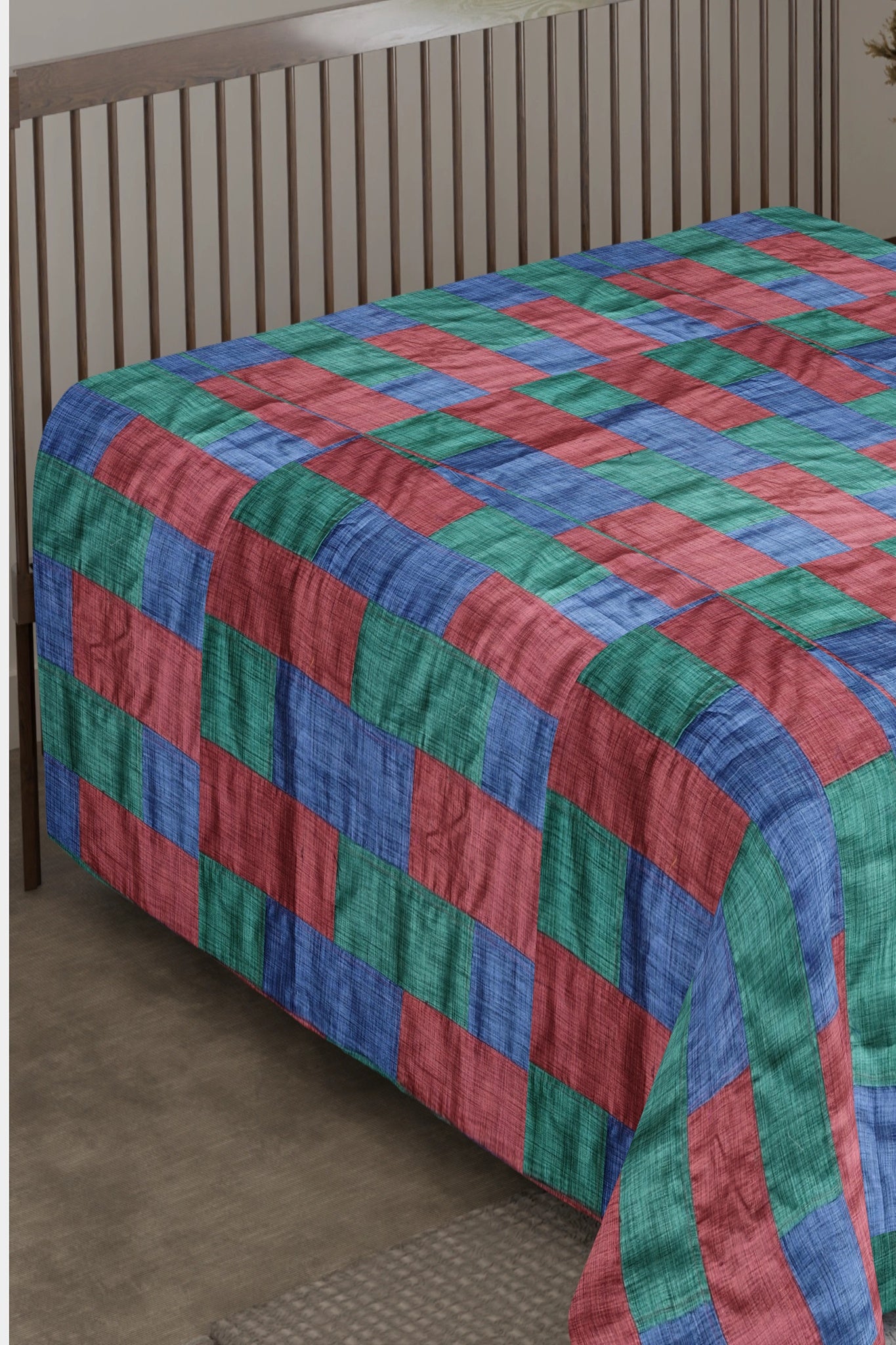 A Tri-Color Tapestry Bedspread featuring a vibrant patchwork of red, blue, and green upcycled textiles, blending artistic design with eco-friendly craftsmanship.